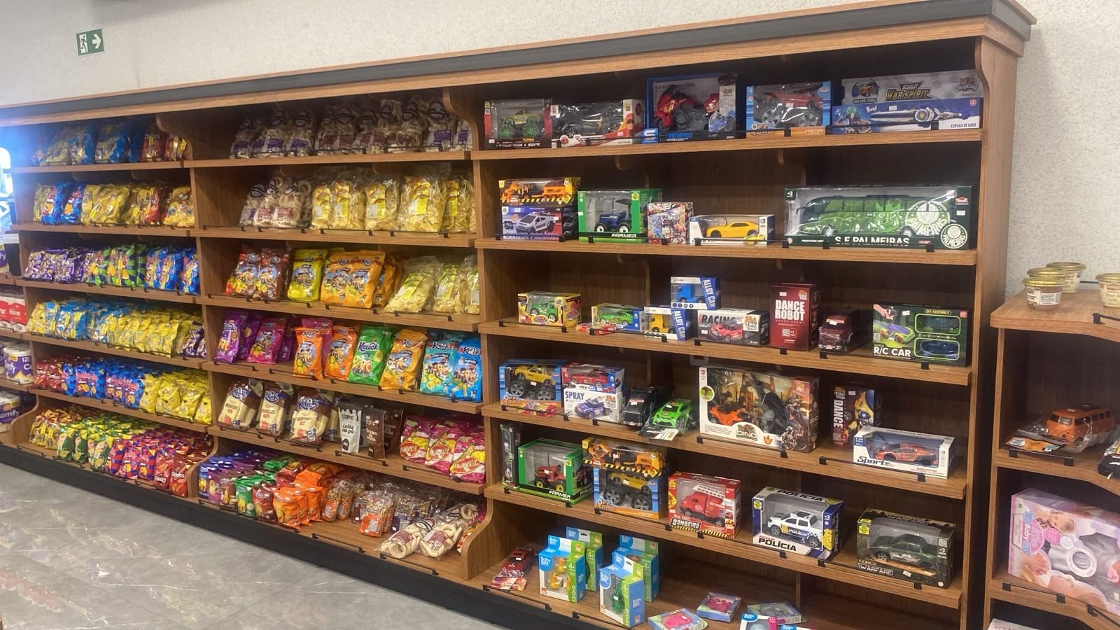 Prateleiras da conveniência com salgadinhos, doces e brinquedos